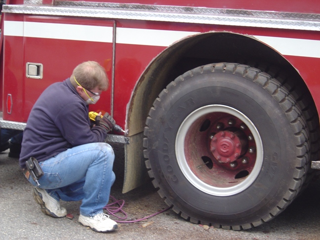 man putting air in firetruck tire